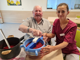 Ein älterer Mann und eine Frau bereiten gemeinsam fruchtige Marmelade in einer Küche vor.