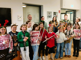 Eine Gruppe junger Musiker in festlichen Pullovern posiert mit ihren Instrumenten.