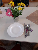 Ein gedeckter Tisch mit einem weißen Teller und einer Blumenvasen.