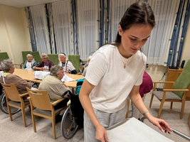 Eine Betreuungskraft bereitet Essen für Senioren in einem Gemeinschaftsraum vor.