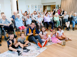 Eine Gruppe von Senioren und Kindern lächelt und hebt die Hände zum Spaß.