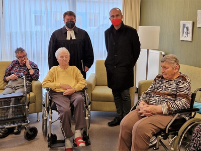 Eine Gruppe von vier Personen, darunter ältere Menschen in Rollstühlen, unterhält sich.
