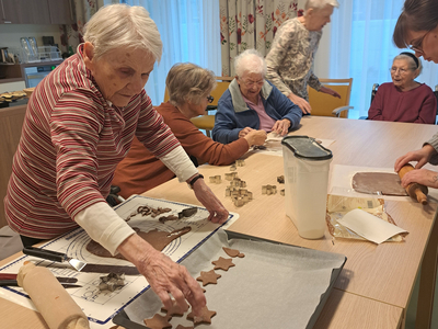 Ältere Damen backen gemeinsam Plätzchen in einem lichtdurchfluteten Raum.