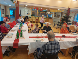 Ältere Menschen sitzen an einem festlich gedeckten Tisch in einem Gemeinschaftsraum.