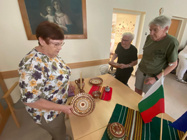 Drei Personen betrachten traditionelles Kunsthandwerk auf einem Tisch.