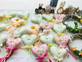 Bunte herzförmige Kissen und dekorative Kränze für Ostern.