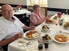 Senioren genießen ein gemeinsames Essen mit mehreren Gerichten und Getränken.