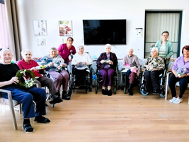 Senioren in Rollstühlen halten selbstgemachte Dekorationen und lächeln glücklich.