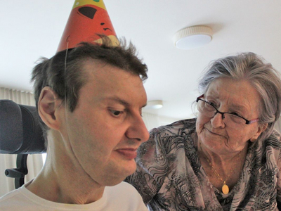 Ein Mann mit Partyhut und eine lächelnde Frau interagieren freundlich miteinander.
