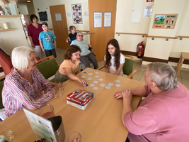 Kinder und Senioren spielen gemeinsam ein Memory-Spiel in einem Gemeinschaftsraum.