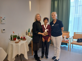 Drei Frauen stehen vor einem Tisch mit Weihnachtsdekorationen und festlichen Objekten.