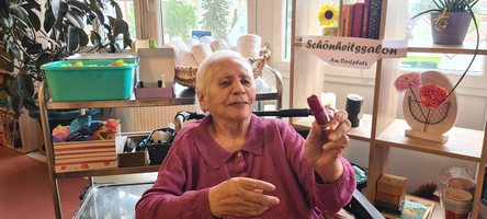 Ein Foto einer Bewohnerin in Neufeld, lächelnd in die Kamera, sieht aus wie im Friseursalon 