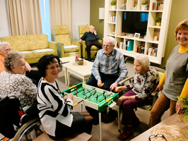 Senioren spielen Tischfußball zusammen in einem gemütlichen Gemeinschaftsraum.