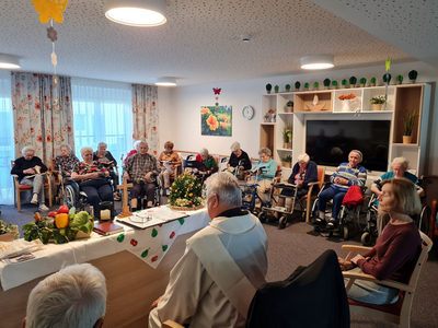 Eine Gruppe älterer Menschen sitzt in einem Raum während einer Feier.