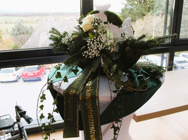 Ein florales Arrangement mit weißen Rosen und Schmetterlingen, dekoriert mit einem Band.