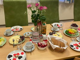 Ein Tisch mit verschiedenen Frühstücksoptionen, inklusive Obst, Käse und Brötchen.