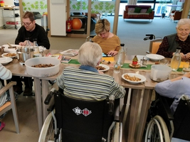 Gruppensitzung mit Menschen, die gemeinsam Essen zubereiten und essen.
