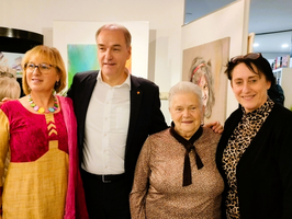 Vier Personen posieren freundlich vor Kunstwerken in einer Galerie.