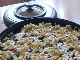 Pfanne mit frischen, frittierenden Teigbällchen auf dem Herd.