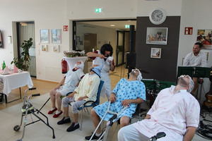 Elderly individuals in a care home enjoying a music performance.