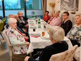Eine Gruppe älterer Menschen sitzt an einem Tisch und genießt eine Mahlzeit.