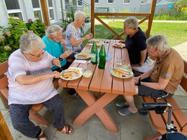 Fünf ältere Personen sitzen an einem Tisch und genießen gemeinsam ein Essen.
