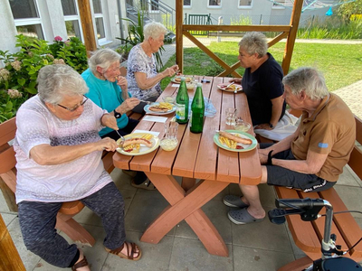 Fünf ältere Personen sitzen an einem Tisch und genießen gemeinsam ein Essen.