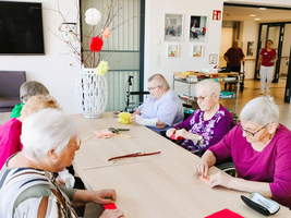 Ältere Frauen basteln gemeinsam an einem Tisch in einem Gemeinschaftsraum.