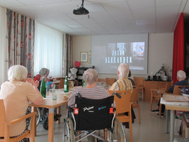 Senioren schauen einen Film in einem Gemeinschaftsraum mit Projektion.