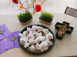 Ein Teller mit Schaf-Papierfiguren und dekorativem Gras auf einem Tisch.