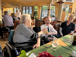 Zwei ältere Menschen stoßen mit Getränken in einem Restaurant an.