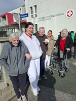 Gruppierung von Pflegekräften und Senioren vor einem Pflegekomplex.