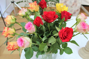 Ein Strauß mit roten, rosa und gelben Rosen in einer Vase.