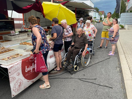 Marktstand mit mehreren Personen, die Gebäck und Süßigkeiten auswählen.