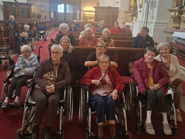 Gruppe von älteren Menschen in Rollstühlen in einer Kirche.