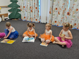 Vier Mädchen in bunten Tütüs sitzen und lesen Bücher.