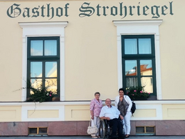 Drei Personen stehen vor dem Gasthof Strohriegel.