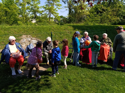 Kinder interagieren mit älteren Menschen im Freien an einem sonnigen Tag.