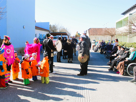 Kinder in Kostümen tanzen vor einer Gruppe von Senioren in Rollstühlen.
