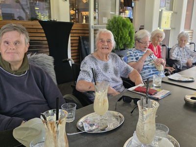 Eine Gruppe älterer Menschen sitzt zusammen an einem Tisch mit Getränken.