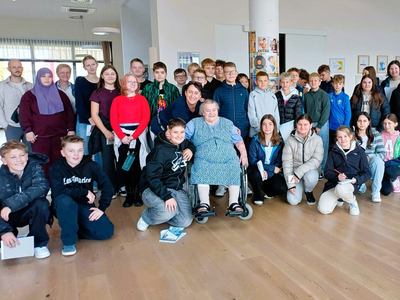 Gruppe von Schülern und einer älteren Frau in einem Gemeinschaftsraum.