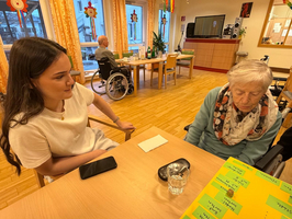 Junge Frau spricht mit einer älteren Dame in einem Pflegeheim.