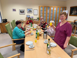 Eine Gruppe von Menschen beim gemeinsamen Frühstück und fröhlichem Zusammensein.