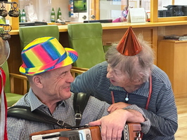 Ein Mann und eine Frau lachen und unterhalten sich mit bunten Hüten.