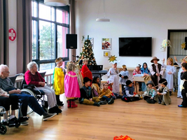 Kinder führen eine Weihnachtsaufführung in einem Gemeinschaftsraum auf.