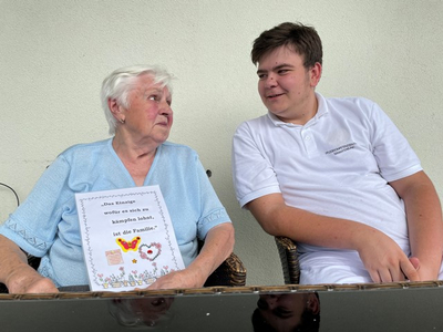Eine ältere Frau und ein Jugendlicher unterhalten sich über Familie.