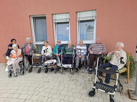 Eine Gruppe älterer Menschen in Rollstühlen sitzt vor einem Gebäude.