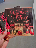 Zwei Gläser Rotwein auf einem Tisch mit Rosen und Kerzen.