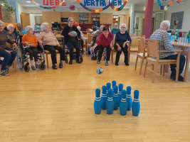 Eine Frau spielt mit einer Kugel Bowling in einem Gemeinschaftsraum.