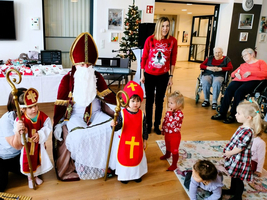 Der Nikolaus sitzt mit Kindern und einer Betreuerin in einem Raum.